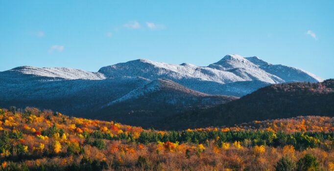 Snow-capped mountains in the distance, with colorful foliage in the foreground.