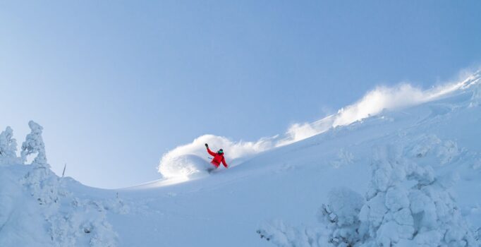 A snowboarder carves a big turn on a mountain in Vermont.