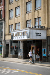 Outdoor view of a downtown theater with patrons walking by on a sidewalk.