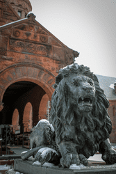 A stone lion carving outside a brown brick Victorian building in the winter.
