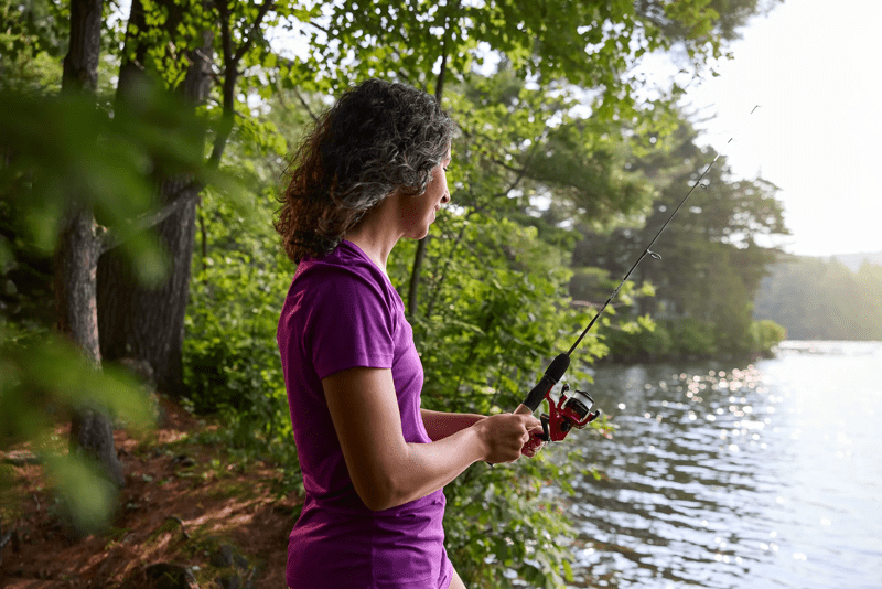 A person fishes from the shore of a lake.