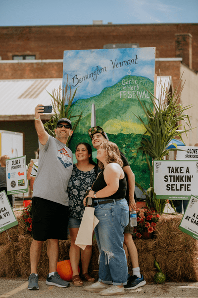 Group of people take a selfie in front of a sign that reads 
