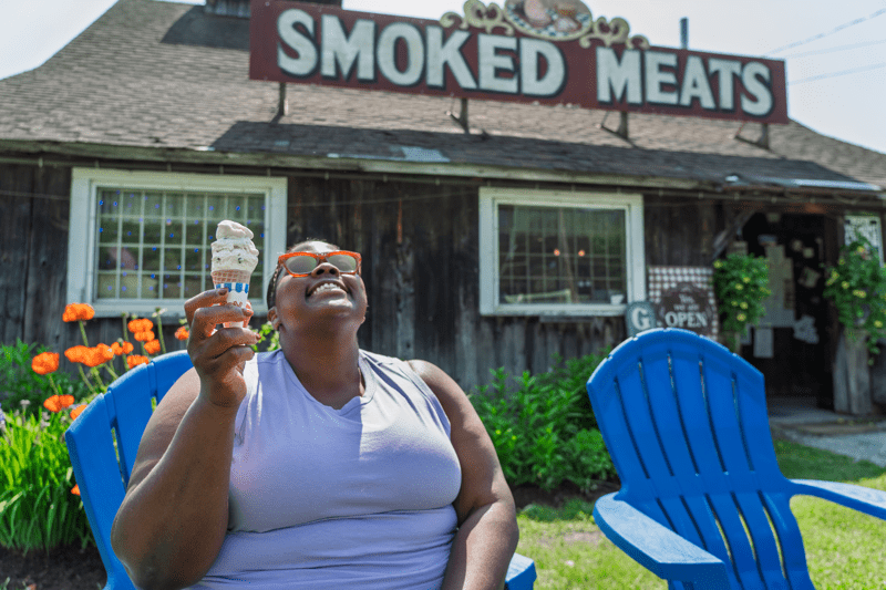 A person enjoys an ice cream cone in a blue chair outside in Vermont.