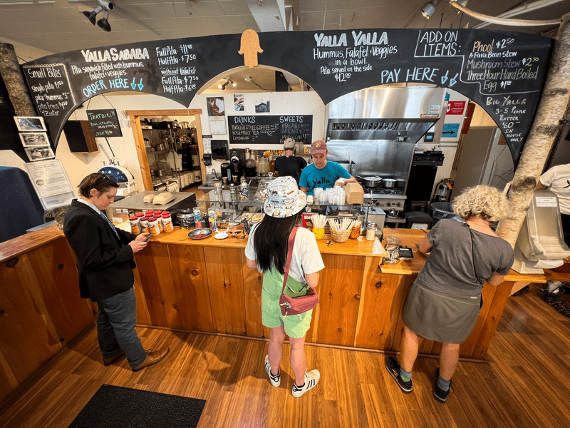 Customers are being served at the counter of a coffee shop.