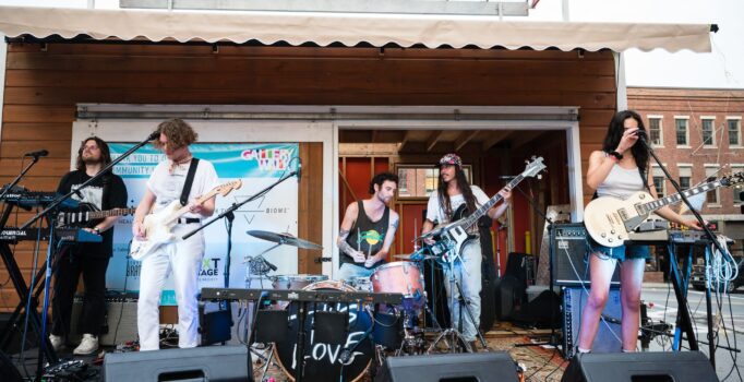 A group of people play live music on an outdoor stage.