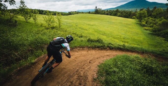 A person rides a mountain bike along a gravel path on a summer day.