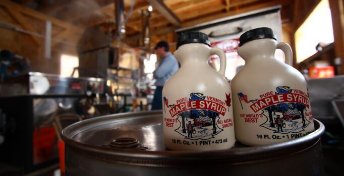 Two small jugs of maple syrup sit on a keg and read Pure Vermont Maple Syrup on the side.