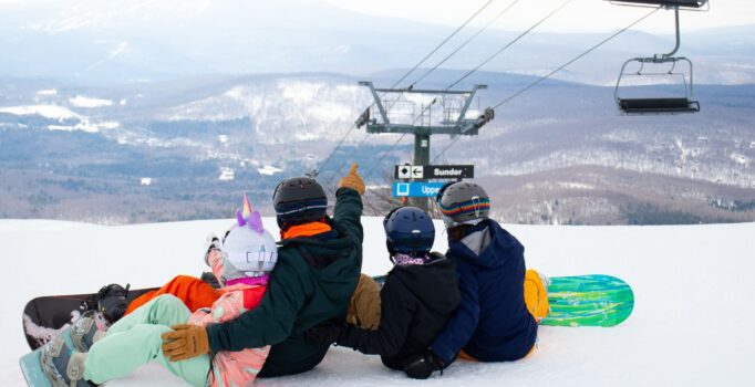 An adult and three children look at the chair lifts on a mountain in Vermont.