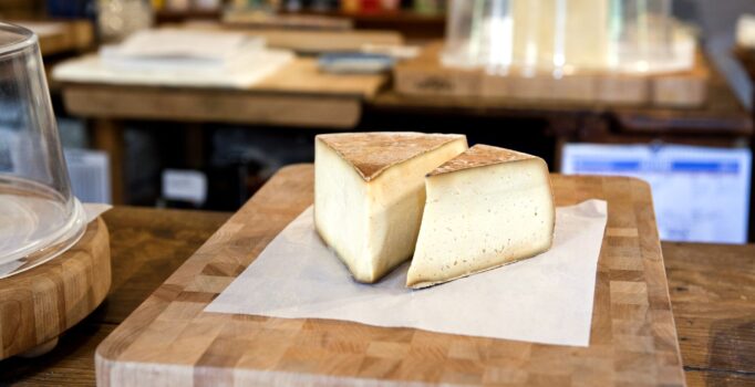 Wedges of cheese sit on a cutting board.
