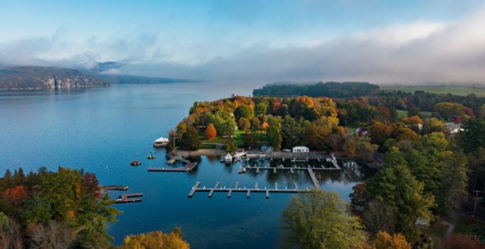 Ariel view of a large lake surrounded by trees in the fall.