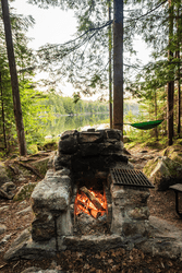 A campfire roars in a stone fire pit outdoors at a campsite.