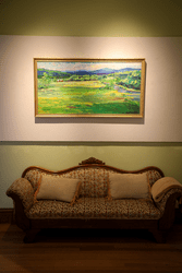 A painting and antique couch are on display in an art gallery.