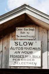 A sign on a covered bridge dating it to 1875 and instructing riders to keep horses at a walk.