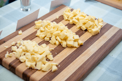 Three piles of cheese pieces lay on a cutting board.