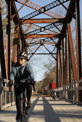 A person bikes across an old railroad bridge.