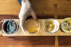 Viewed from above, four tasting glasses with beer are sitting on a table.