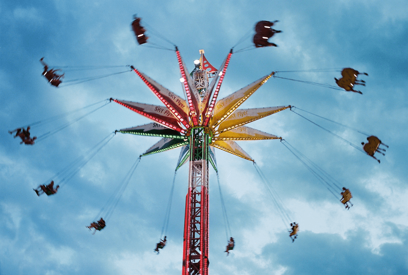 Groups of people ride a swing ride at an outdoor carnival.