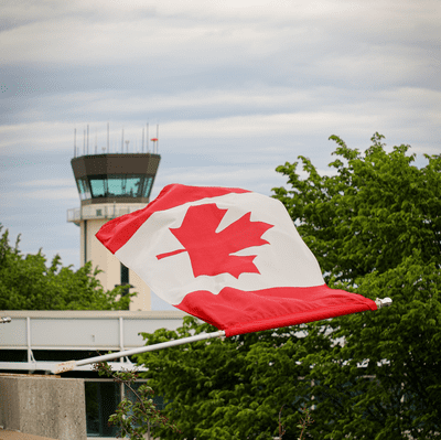 A Canadian flag hangs off a flag pole on the side of a building.