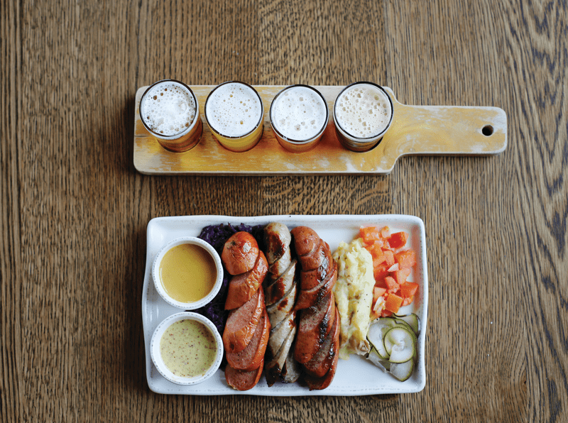Top-down view of plate of food and a flight of beer.