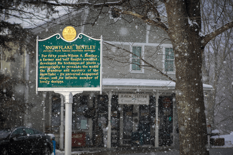 A marker by the side of the road in winter tells the story of Wilson Snowflake Bentley.