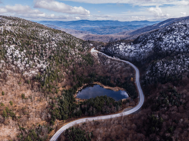 Seen from above, a long road winds through snow-dusted mountains.