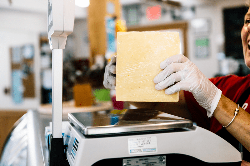 A person weighs a block of cheese.