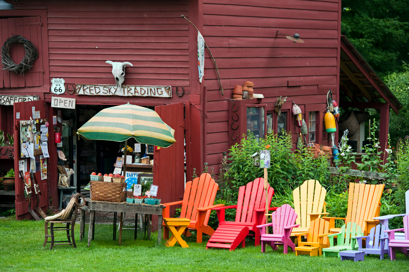 A red barn with art outside and visible within the door in the summer.