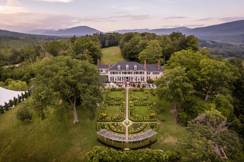 Seen from above, an old mansion with farmlands spread around it in the summer.