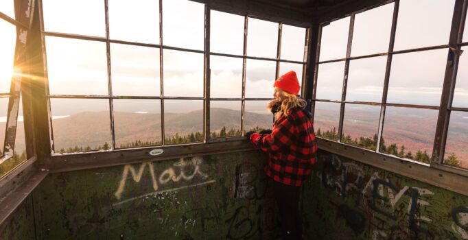 A person looks out the windows of a tower at the top of a mountain.