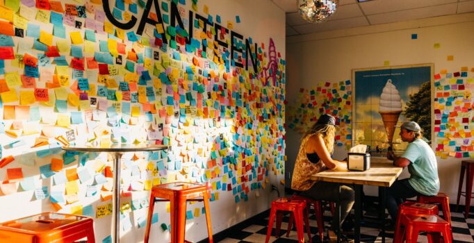 Notes cover the walls of Canteen Creemee Company while two enjoy Creemees at the table.