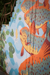 A colorful mural on a wall showing fish and lily pads