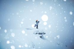 A snowboarder stands on a mountaintop in Vermont.