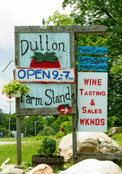 A sign reading “Dutton Farm Stand” outlining what’s on offer in the summer outside.