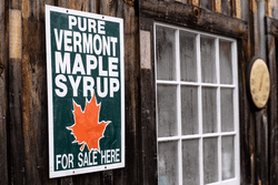 The side of a wood barn with a Pure Vermont Maple Syrup for Sale Here sign.