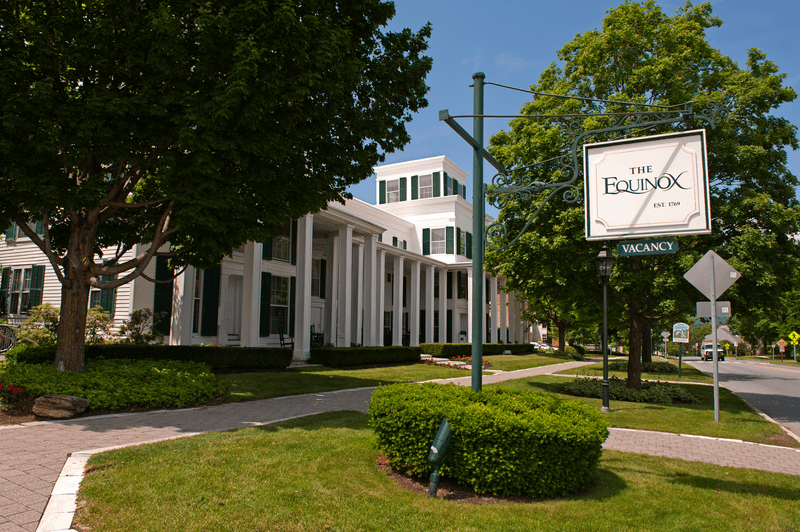 A large white building with an Equinox sign out front on a sunny day.