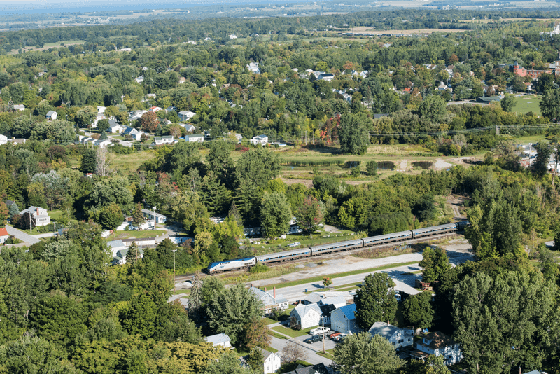 Seen from above, a train crosses a bridge in the summer.