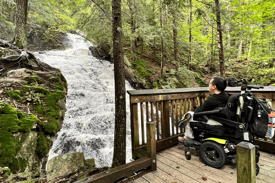 A person in a wheelchair seen from behind as they look at a waterfall view.
