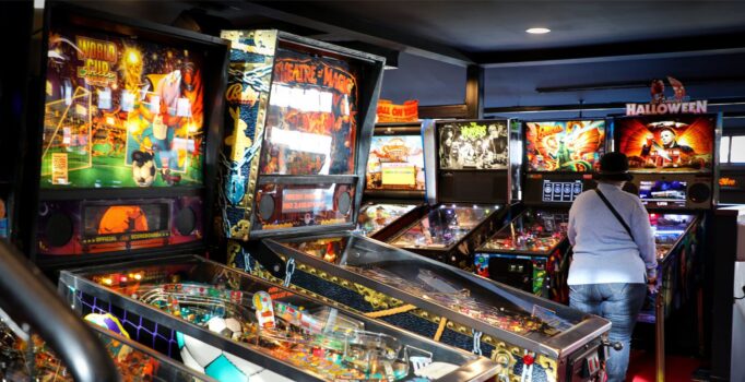 Pinball machines sit in an arcade.