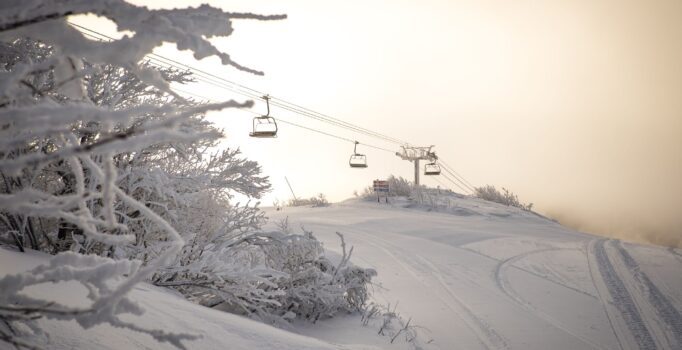 The top of a snowy mountain with a ski lift running across.