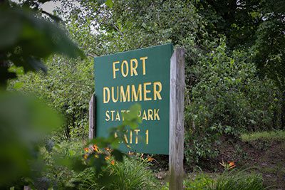 Outdoor park sign reading Fort Dummer State Park, surrounded by trees and bushes.