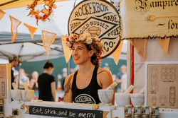 A person works a booth while wearing a crown with heads of garlic on it.