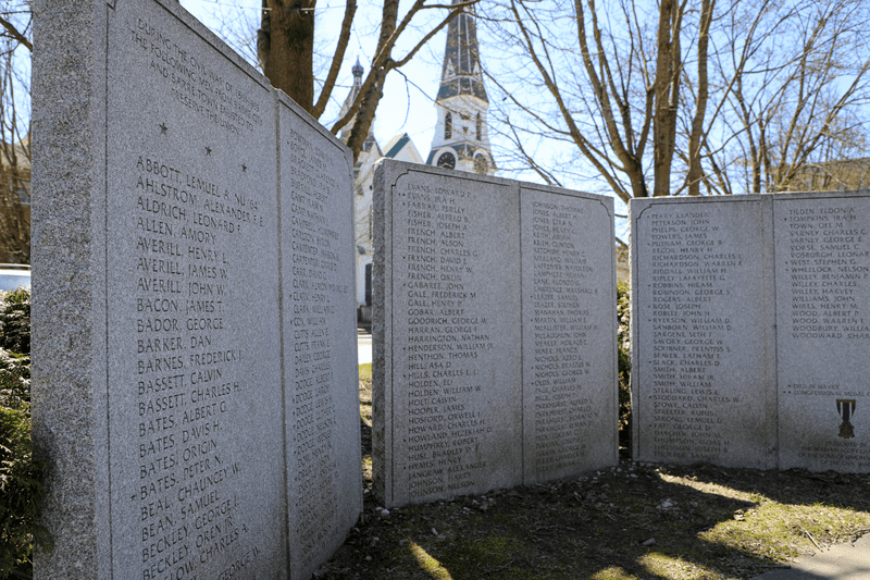 Three granite pieces are inscribed with lists of names in an outdoor park.