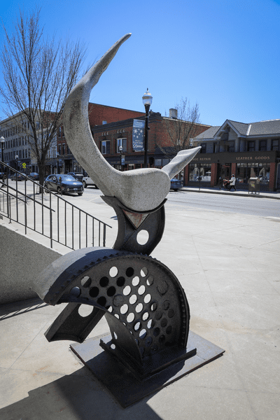 A granite piece of art is on display outdoors on a sunny day.