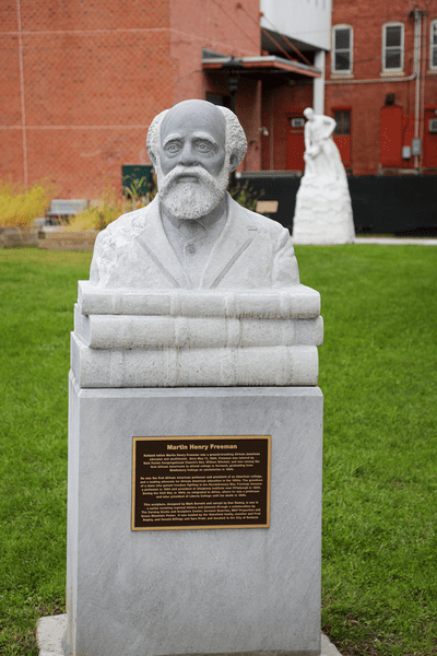 A plaque mounted on a granite sculpture of Martin Henry Freeman.