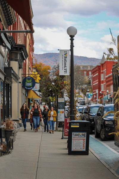 A group of people walk toward the camera within a downtown scene of Rutland, Vermont.