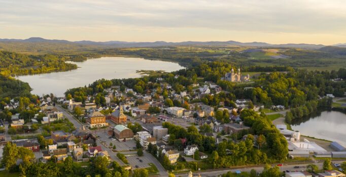 A large lake surrounded by mountains with a downtown on the shore, as well as docks and boats.