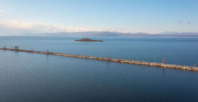 A jetty crosses Lake Champlain. An island appears in the distance.
