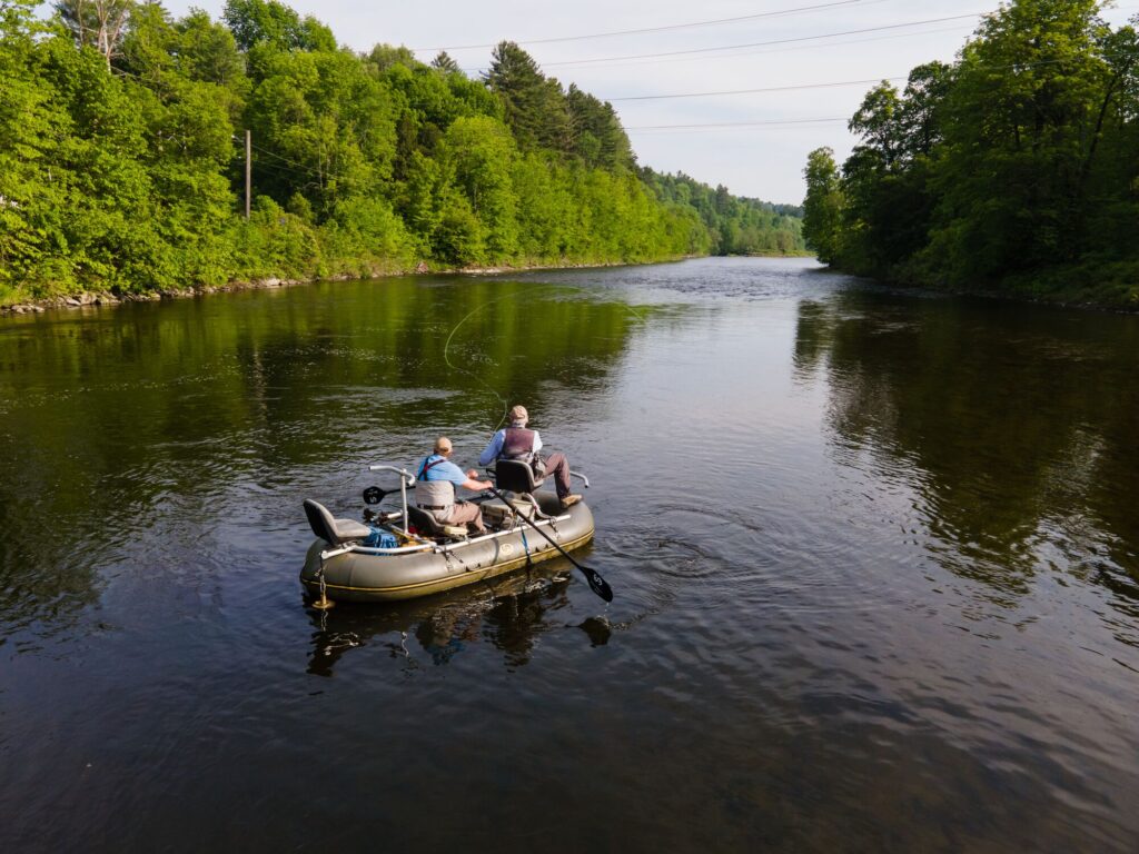 People on a boat fly fishing in a river in the spring