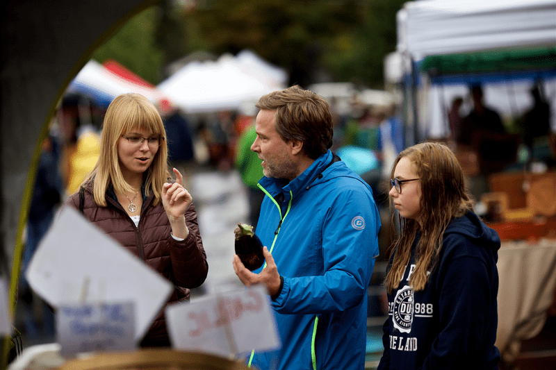 A family considering produce at the Montpelier Farmers Market.