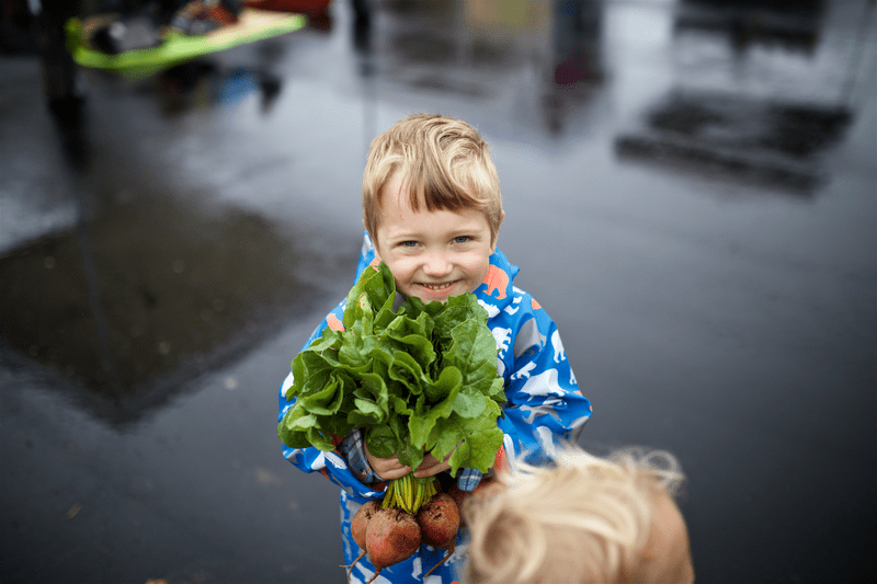 A child holds produce procured at the Montpelier Farmers Market.